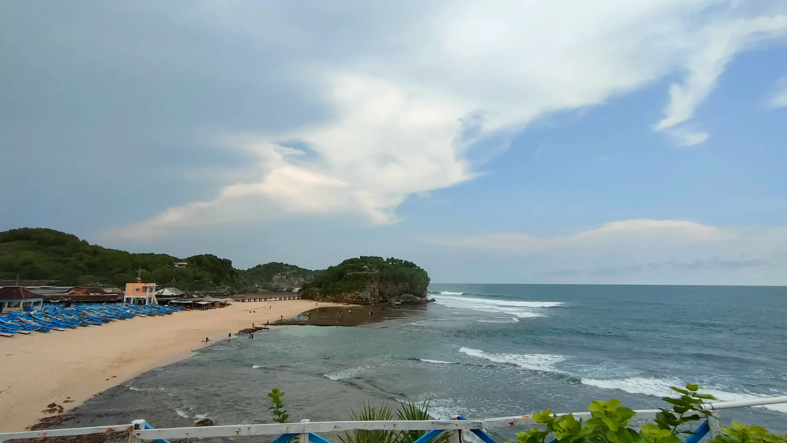 Pantai Gunungkidul Yogyakarta dengan hamparan pasir putih, ombak, dan tebing karang.